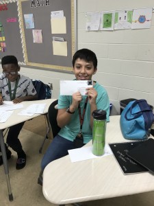Male student smiling and holding up envelope.