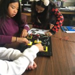 Three students doing an engineering experiment using a circuit board.