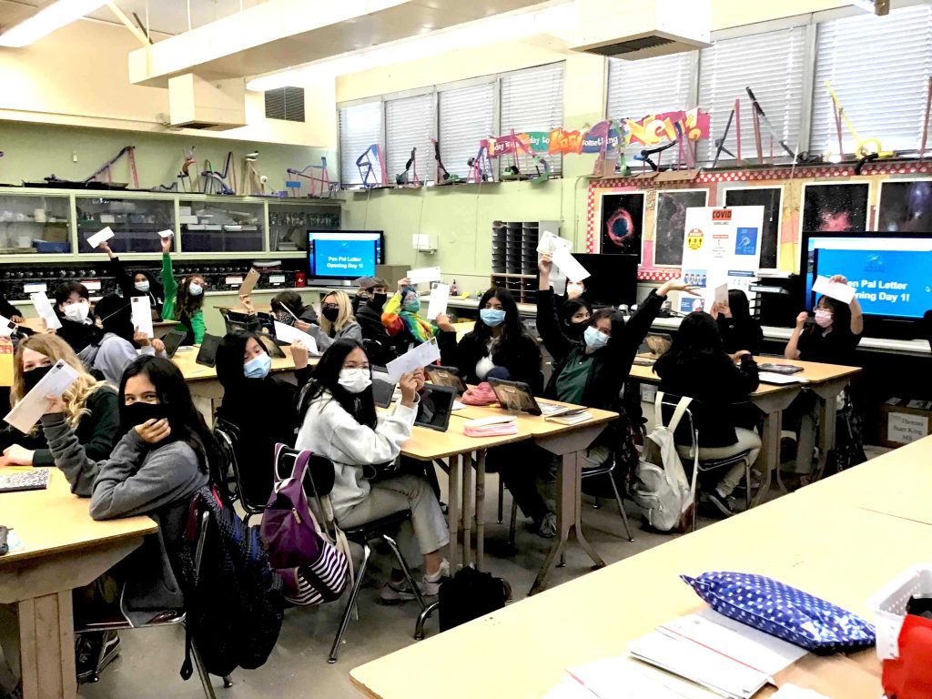 Classroom of pre-scientists hold up their letters from STEM pen pals.